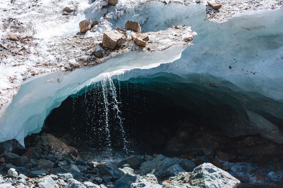 Le yéti existe-t-il vraiment? L’ADN ramène la piste vers les ours A picturesque view of a melting ice cave with water flowing, surrounded by snow and stones.
