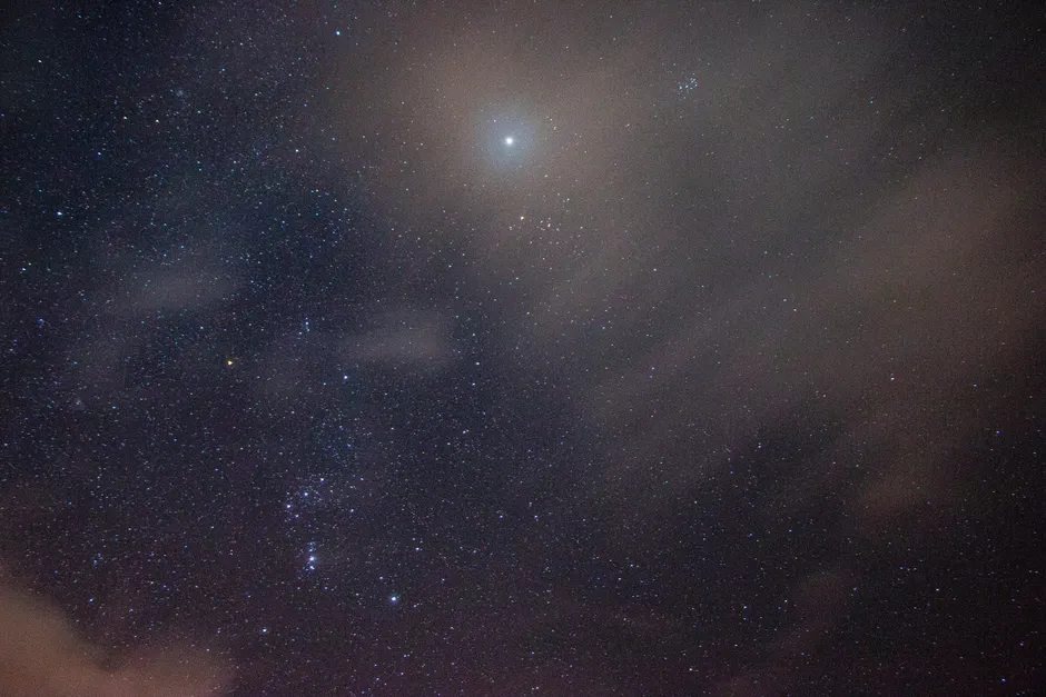 Les OVNI sont-ils vraiment confirmés par les gouvernements? A star-filled night sky with scattered clouds and a bright star illuminating the darkness.