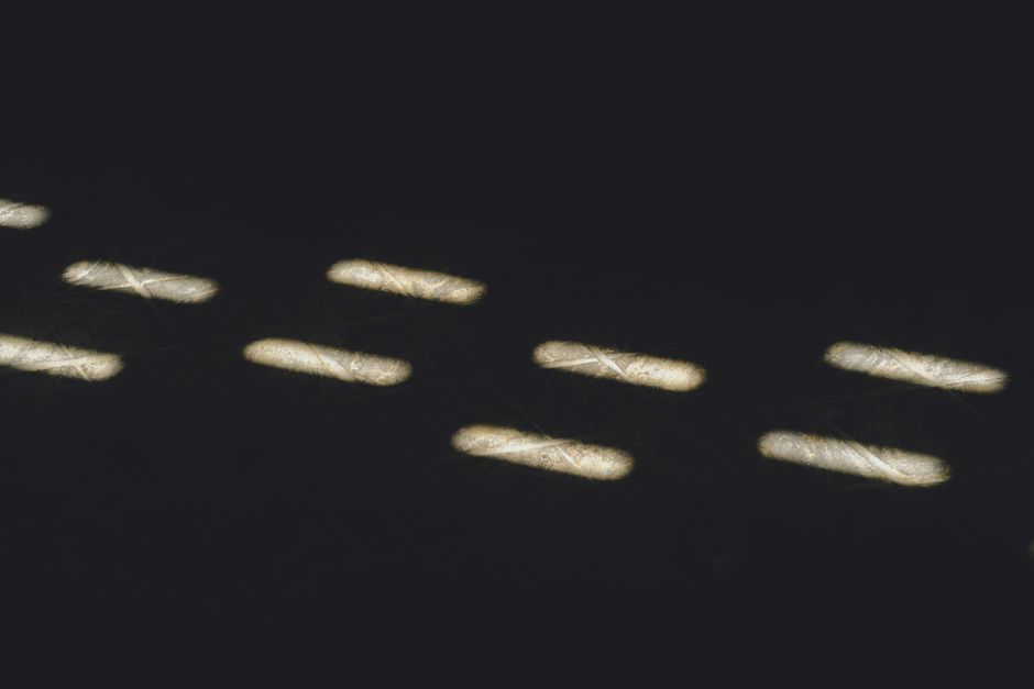 Abstract image of light patterns resembling morse code on a dark background.