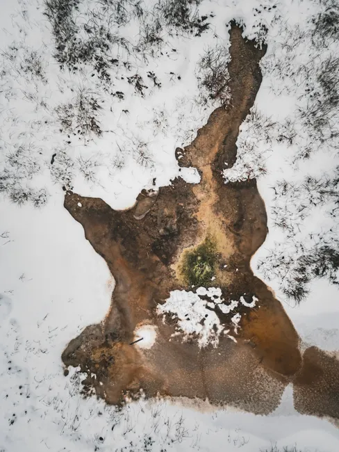Aerial photograph showcasing a frozen lake partially covered by melting snow, creating unique patterns.