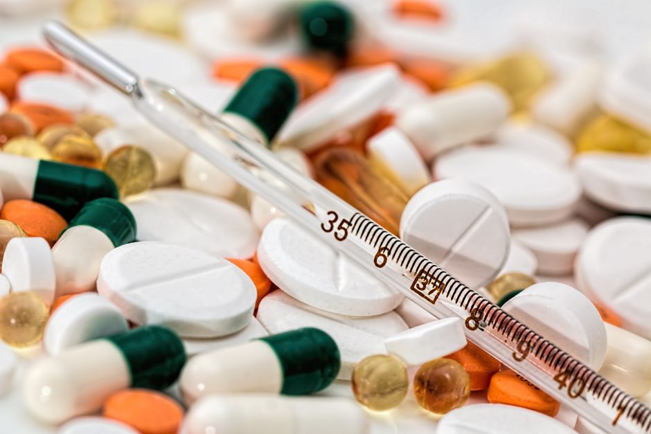 Les antibiotiques guérissent-ils vraiment la grippe? Close-up image showing various pills and a thermometer, emphasizing health and medicine.