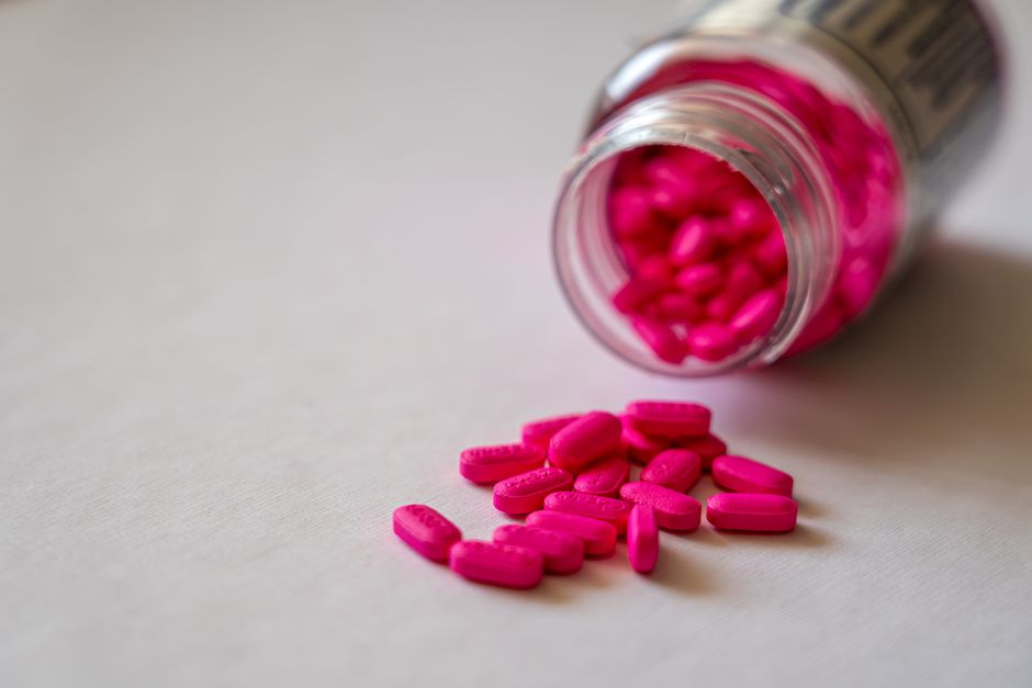 Le ketchup était-il vraiment vendu comme médicament? Close-up of an open bottle spilling pink pills onto a surface, indicating medication use.