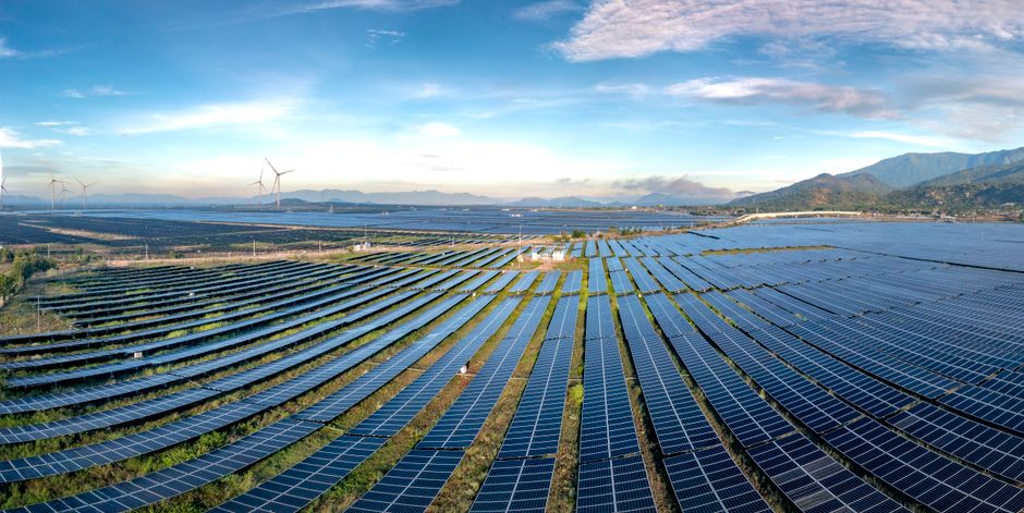 Le monde pourrait-il fonctionner uniquement avec des énergies renouvelables? Expansive solar farm and wind turbines harnessing renewable energy at sunrise, showcasing sustainable technology.