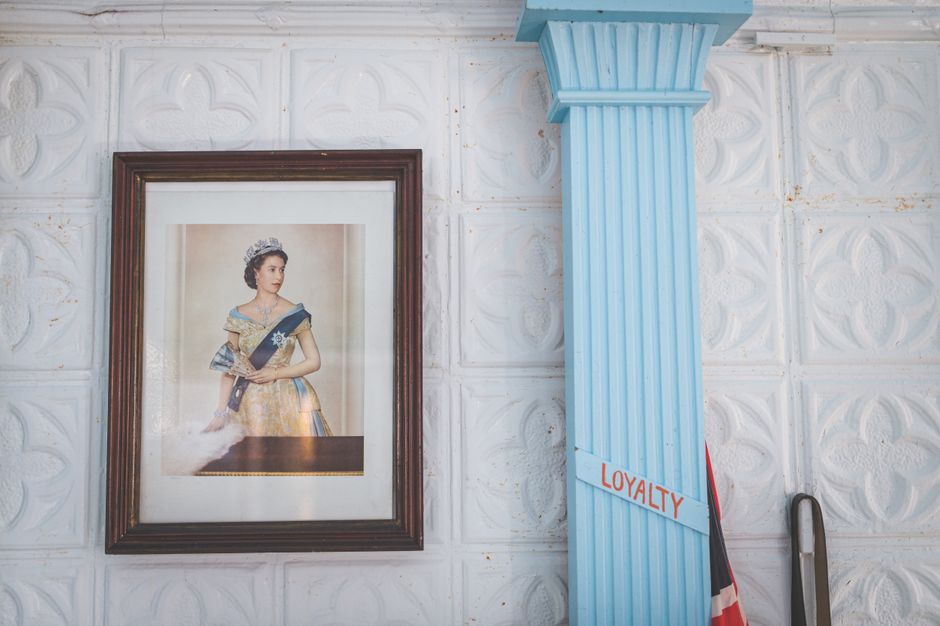 Framed portrait of a queen beside a blue column with loyalty sign.