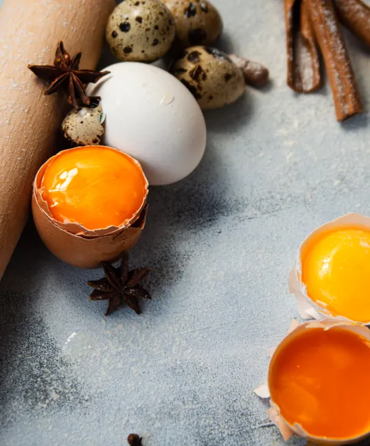 Fresh egg yolks and baking ingredients arranged for food photography. Ideal for culinary themes.