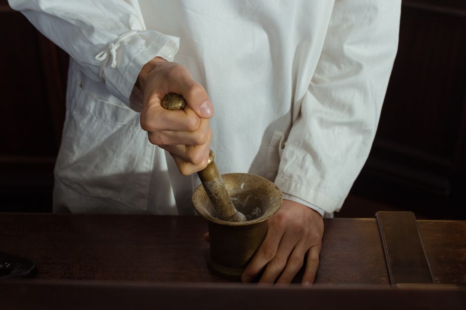 Les momies égyptiennes étaient-elles vraiment réduites en poudre comme remède? Pharmacist grinding ingredients using a mortar and pestle. Traditional pharmacy preparation.