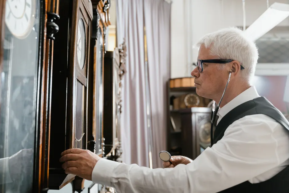 Le jeûne intermittent est-il vraiment efficace? Senior man using stethoscope to check antique clocks displayed indoors, adding scholarly touch.