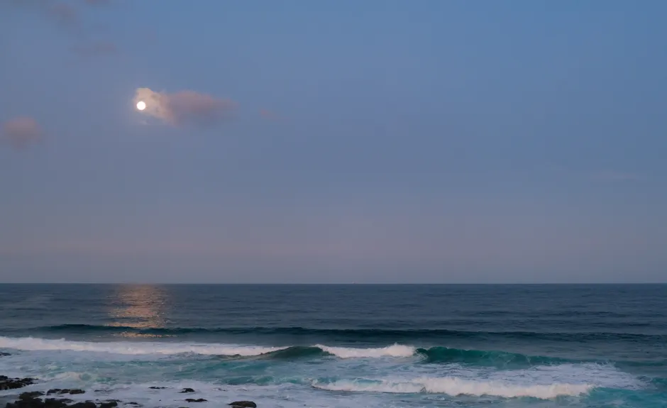 La Lune influence-t-elle vraiment les marées? Serene image of ocean waves under a moonlit sky, capturing nature's tranquil beauty.