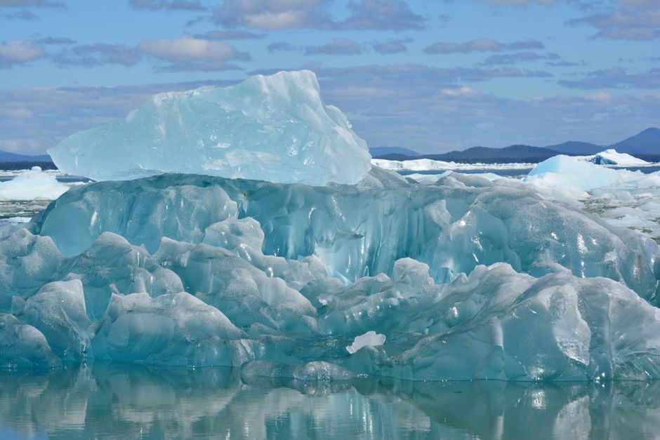 L’Arctique sera-t-il libre de glace d’ici 2050? Stunning iceberg captured in clear Arctic waters, highlighting melting ice and climate change impact.