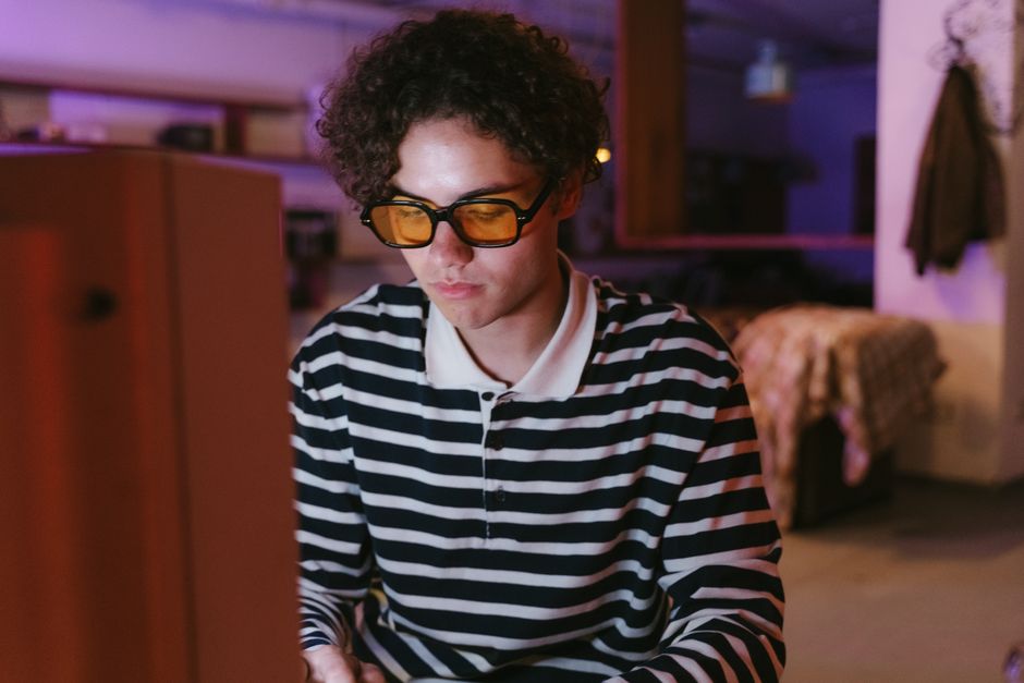 Les écrans abîment-ils vraiment les yeux? Le verdict des études Teenager wearing eyewear focused on using a desktop computer indoors with a retro vibe.