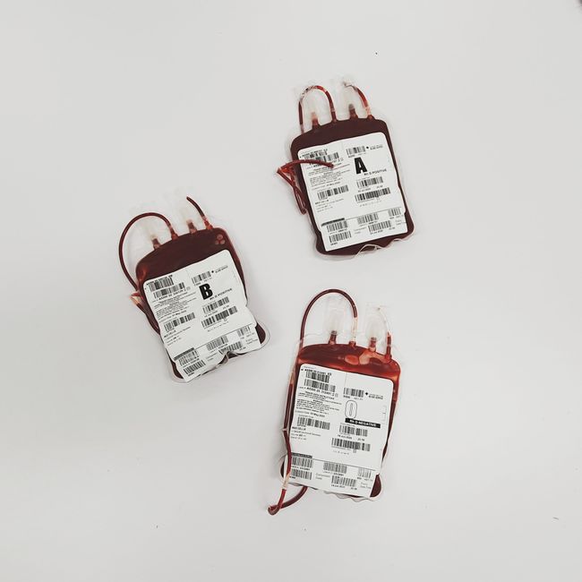 Three bags of blood for donation labeled with different blood types on a white surface.