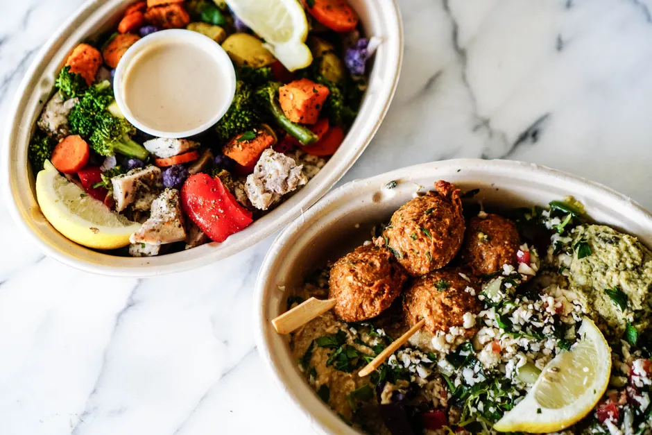 Le houmous est-il vraiment un plat sain? Top view of two vibrant Mediterranean bowls featuring fresh vegetables and falafel.