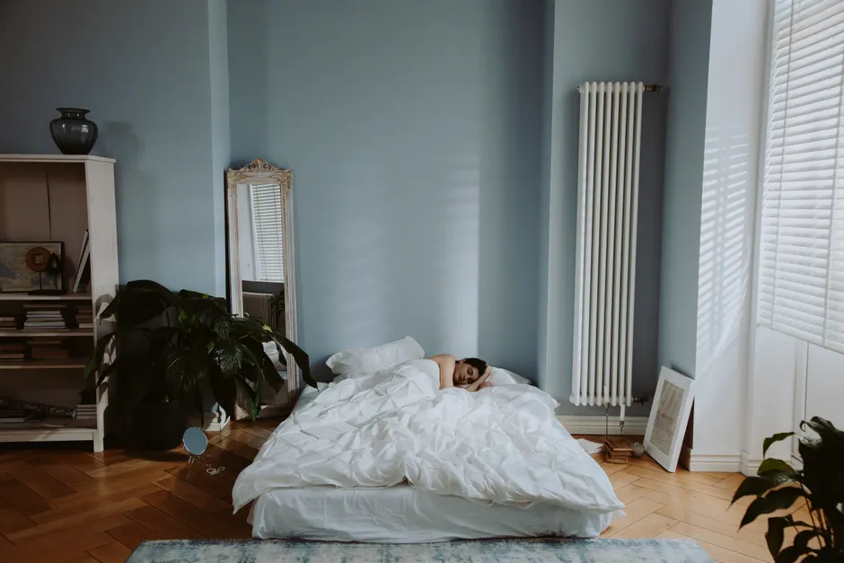 Woman sleeping peacefully in a cozy and stylish bedroom with soft natural light.